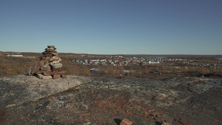 A pile of stones in the foreground with Nunavik in the background.