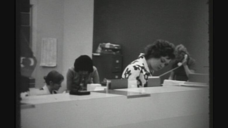 In this archival black and white CBC News image, employees work behind a counter at a Bank of Montreal branch at Vancouver General Hospital, after it was robbed at gunpoint on April 27, 1971. It was at the time the largest bank robbery in B.C. history, in which gunmen stole $2.4 million in today's money.