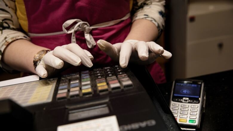 Hands operate a cash register.