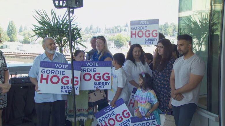 A range of people with signs reading 'VOTE Gordie Hogg Surrey First'.