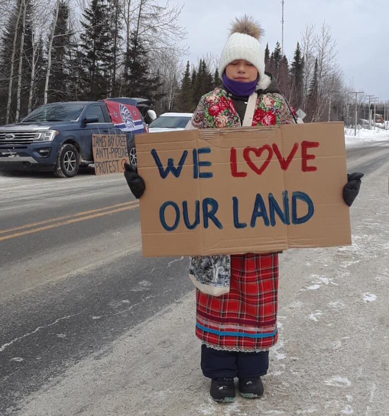 A child holds a placard saying, We love our land.