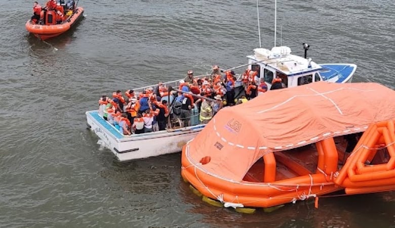 Passengers are seen wearing life-jackets after being evacuated from the MV Holiday Island.