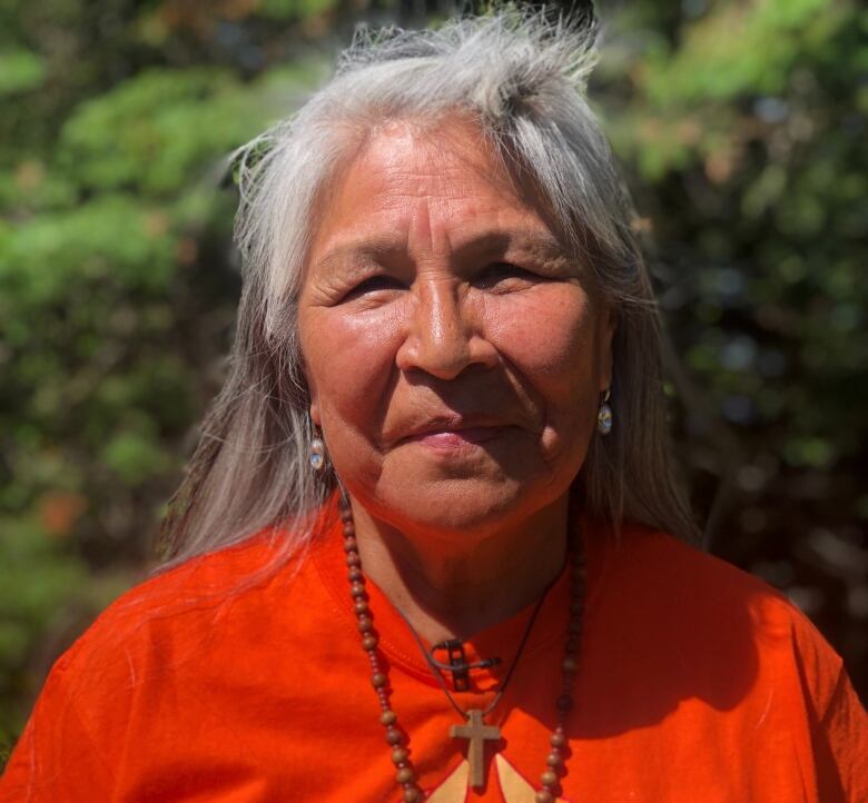 A person wearing an orange shirt stares ahead.