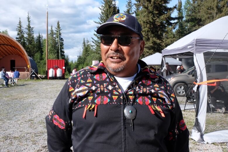 Smiling man in western shirt, ball cap.