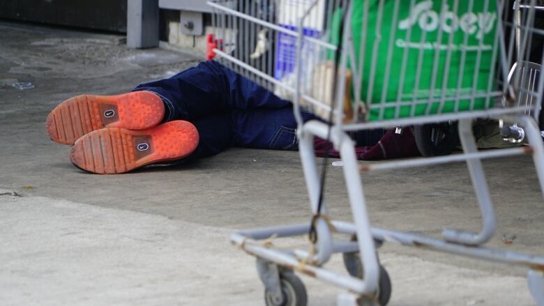 A homeless man sleeps on the pavement below a storefront window on Dundas Street East in downtown London, Ont.                                