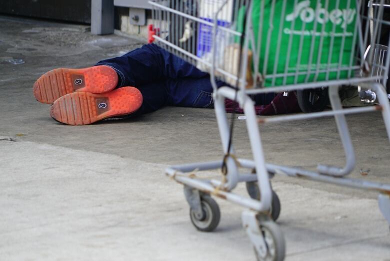 A homeless man sleeps on the pavement below a storefront window on Dundas Street East in downtown London, Ont.                                