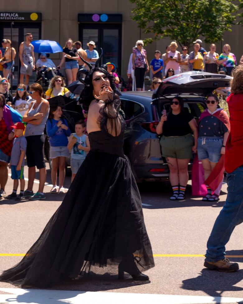 Drag queen with long black hair dressed in long black gown