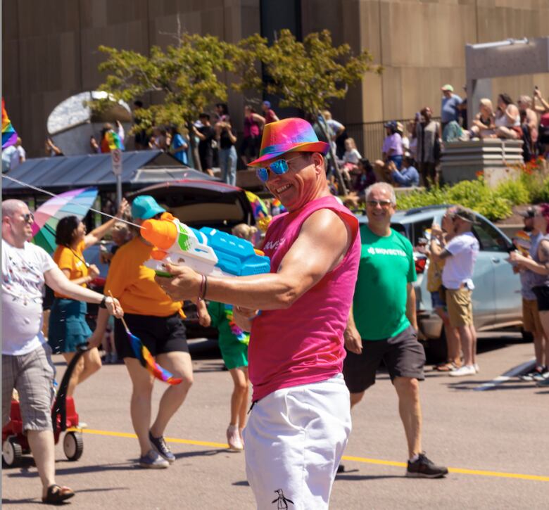 Man in pink hat and shirt holding a water squirting play gun