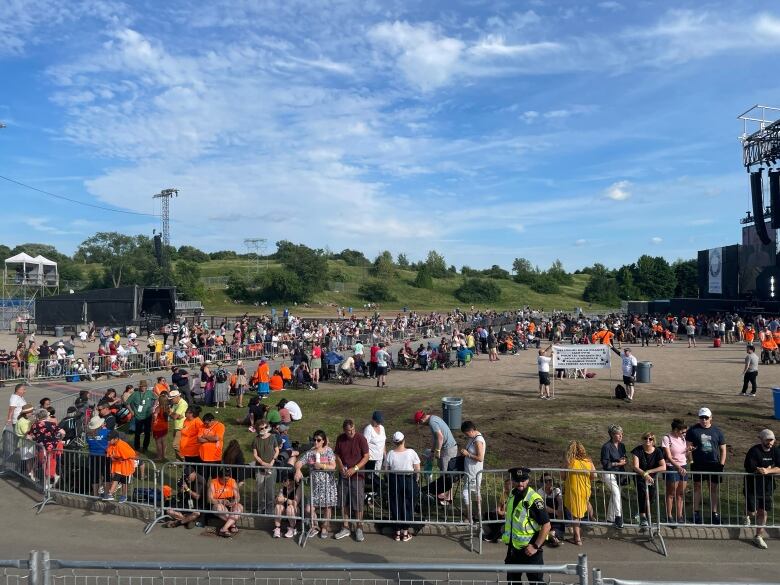 A sparse crowd in a large field in front of a stage.