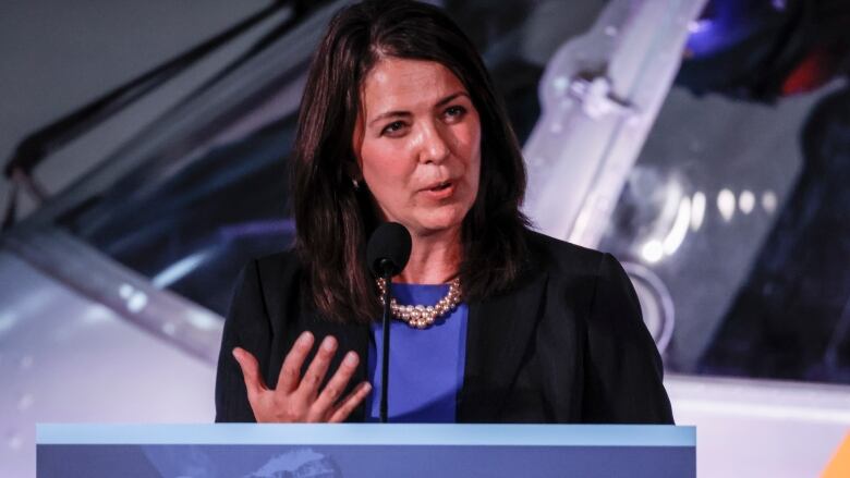 A woman stands at a podium and speaks.