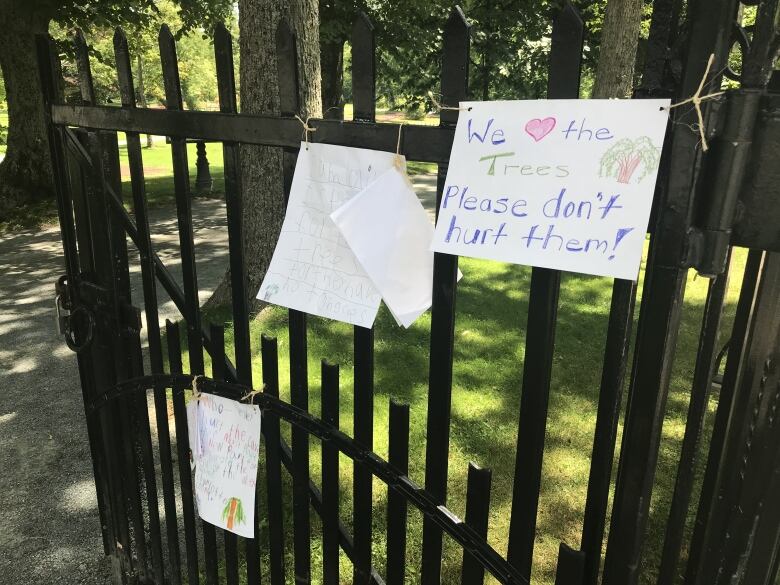 Three signs with messages of support for the Halifax Public Gardens are tied to a fence at the gardens. 