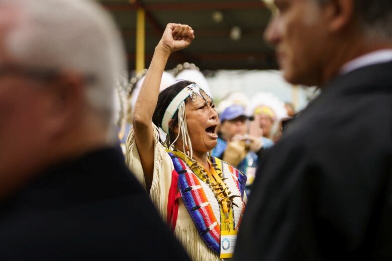 A Cree woman raises her fist as she sings a message to Pope Francis.