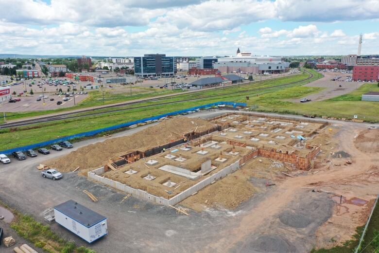 A construction site shown with concrete structures and foundations with the Moncton skyline in the background. 