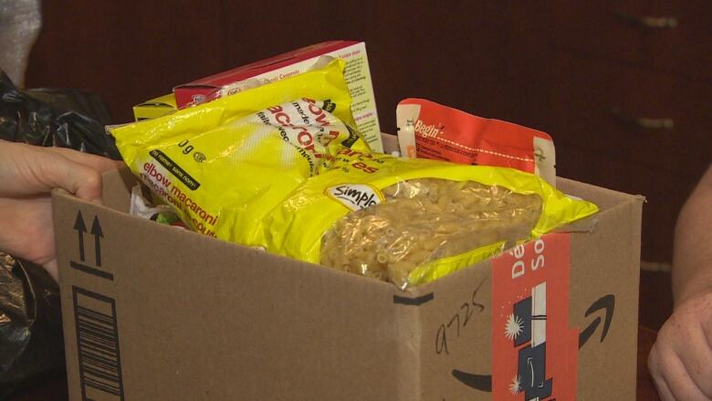 A person holds a box of food items.