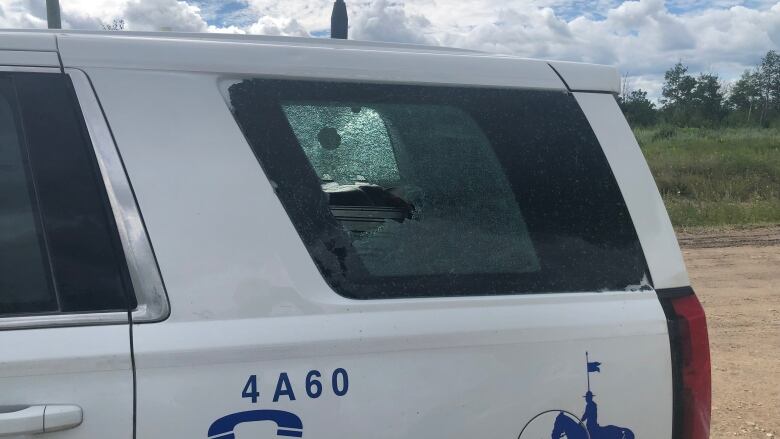 A broken back window of an RCMP vehicle.