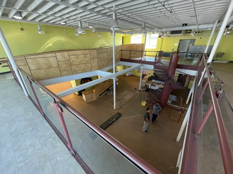 An overhead view of the inside of a building undergoing renovation, with two people standing on the ground floor.