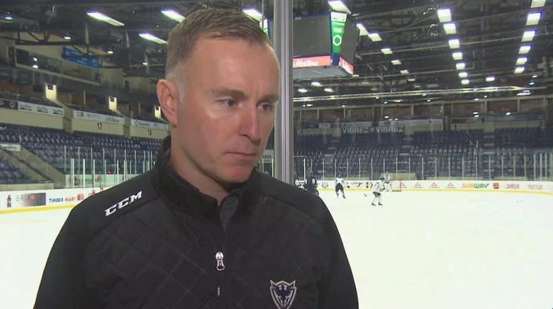  A man stands in front of a hockey rink. 