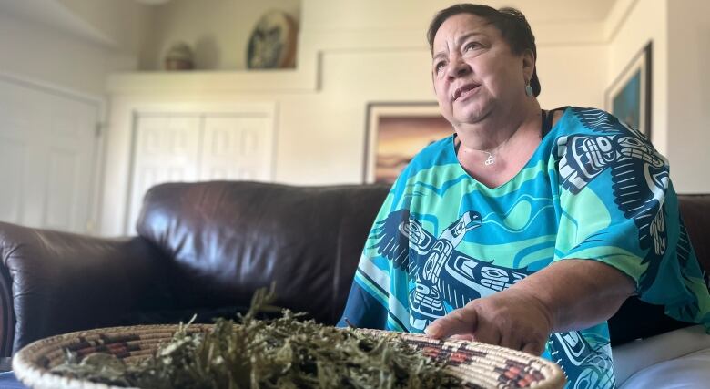 A woman looks up over a bowl of sage.