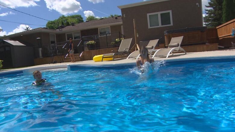 Children in a pool, with an adult in the background.