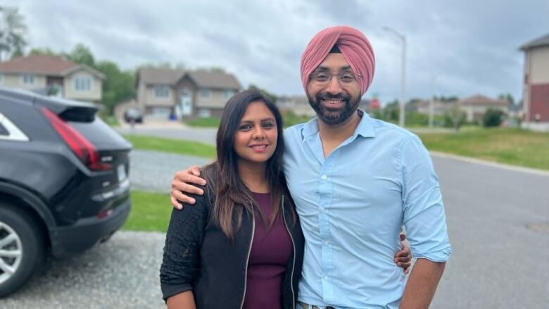 Ishmeet Singh and Suchita Bali stand in a driveway in the Minnow Lake neighbourhood.