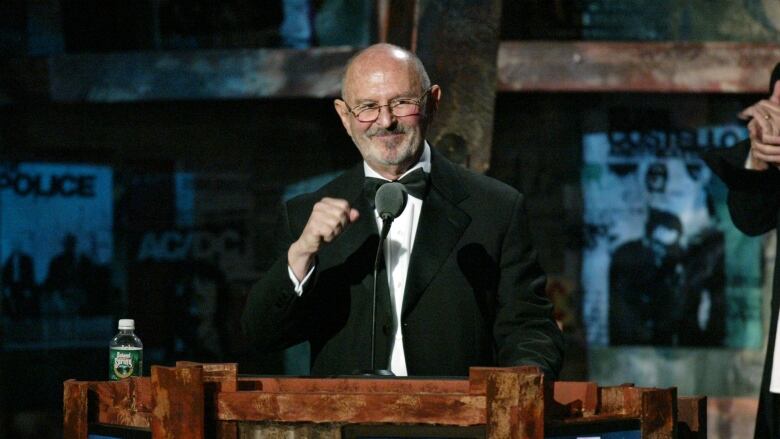 A man stands at a podium, his hand in a fist.