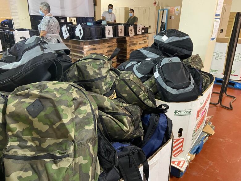 Boxes of school backpacks are on a table.