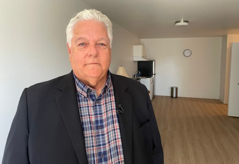 man with white hair standing in small apartment