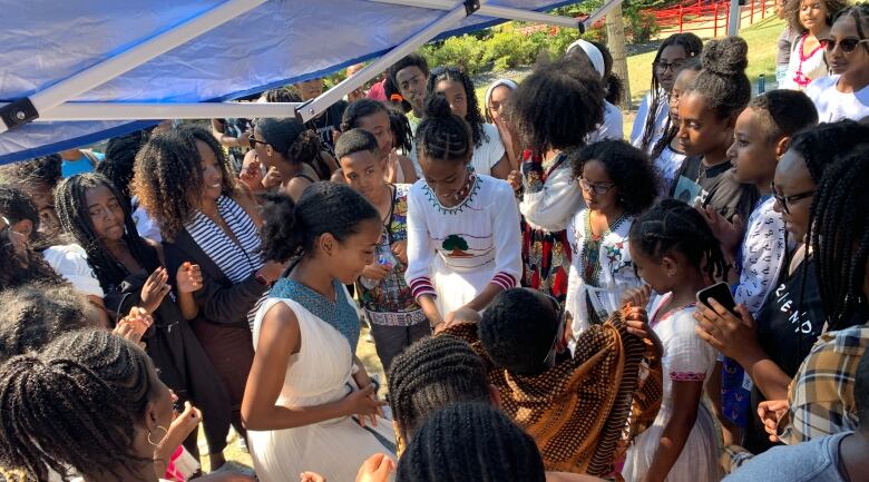 A crowd of children dance under a tent. 