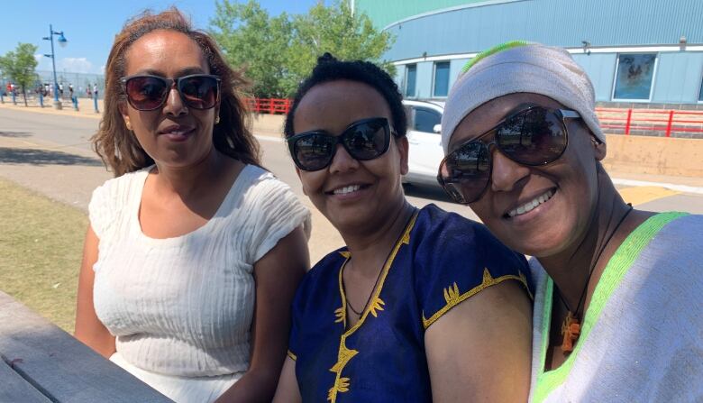 Three women sit at a picnic table. 