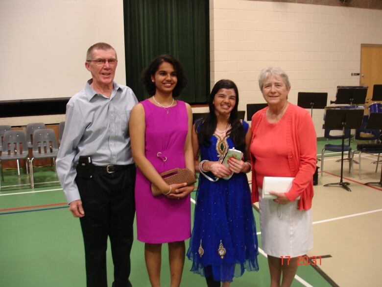 Four people pose for a photo inside a school.