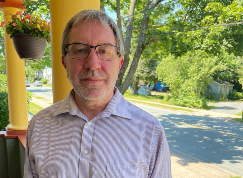 A Halifax man stands on his front porch with a tent encampment behind him. 