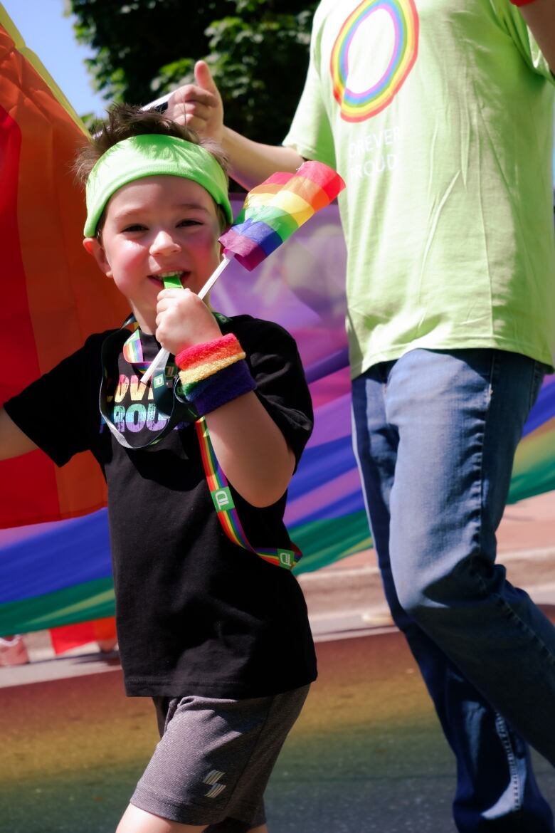 young boy holding small Pride Flag and blowing a whistle 