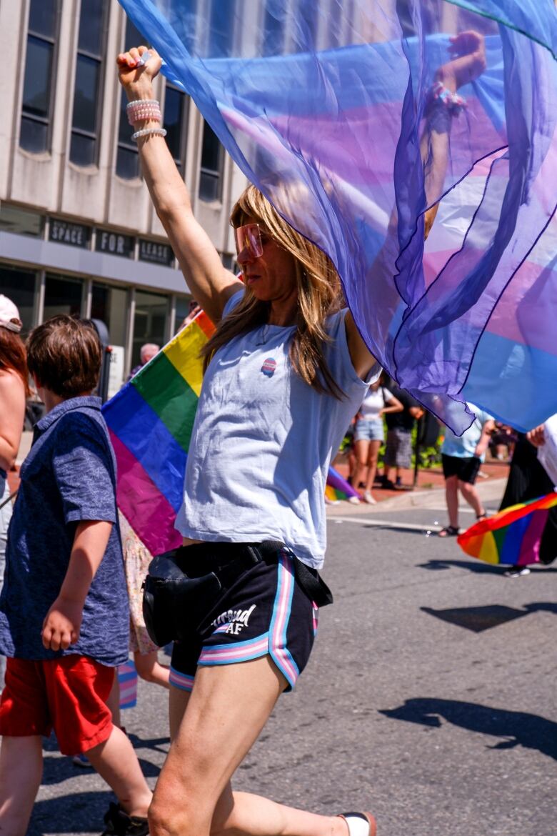 Girl holding up a colouful flag at Pride Parade