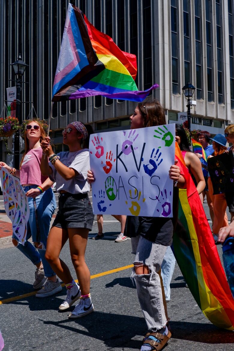 People with signs and flags walking in Pride parade