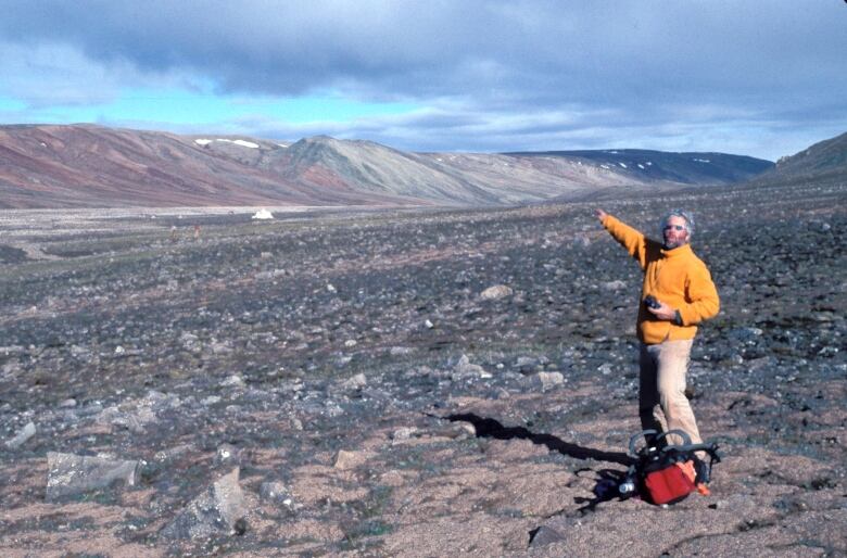 A portrait of a man pointing into the broad landscape around him.