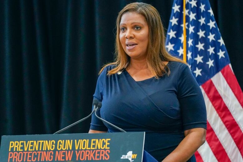 A woman speaks at a podium with the American flag in the background.