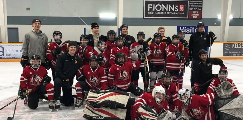 A young boys hockey team pose on the ice with several Hamilton Bulldogs players. 