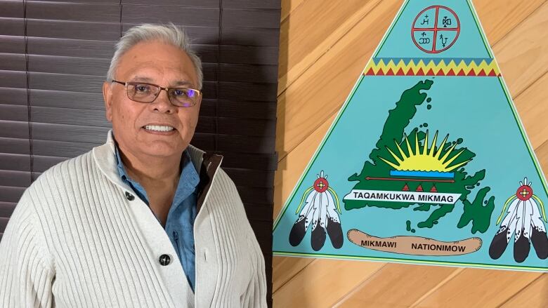 Chief Joe stands next to the Miawpukek First Nation emblem.