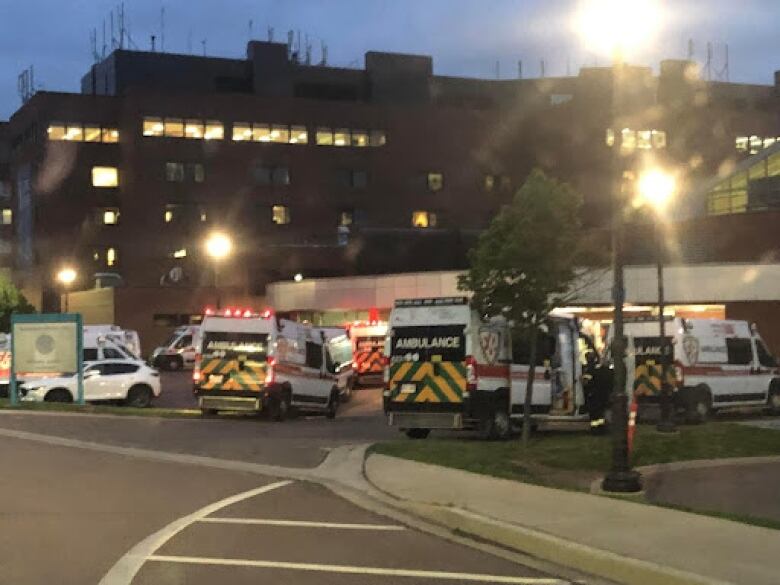 Multiple ambulances outside a multi-storey building in the dark.