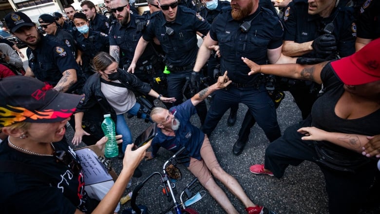 Vancouver police officers arrest multiple people during a melee while the city was dismantling tents on East Hastings in the Downtown Eastside neighbourhood in Vancouver, British Columbia on Tuesday, Aug. 9, 2022. 