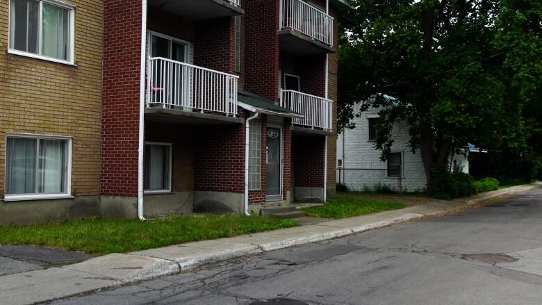 A drab apartment building next to an old home.