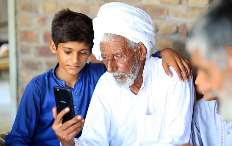 A man looks into a smartphone, surrounded by young relatives.