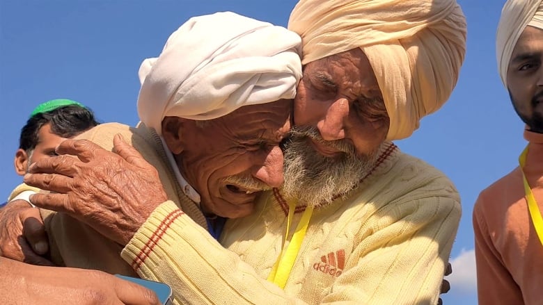 Two men with turbans embrace.