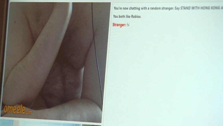 A screen capture of a man with a hairy chest on on a website called Omegle. He is seen in a video chat window and beside him is a text chat window. 