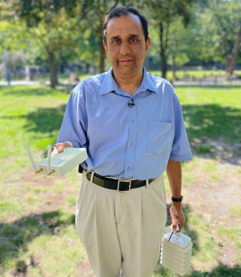 Raja Sengupta holding a white sensor that looks like a wifi modem