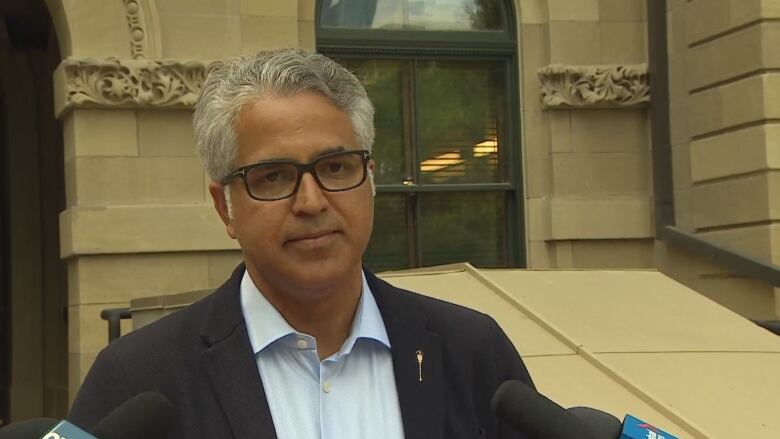 A man wearing glasses speaking into a microphone