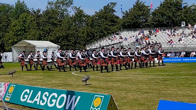 Bagpipers and drummers perform on field.