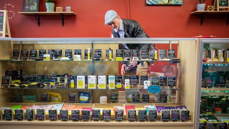 A man stands behind a counter with a range of cannabis products.