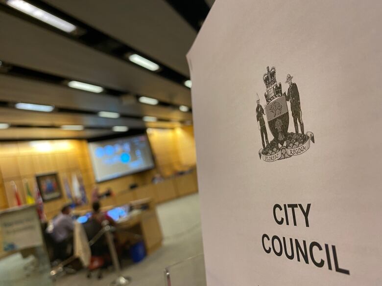 A Regina city council agenda is interposed with the city council chambers. 