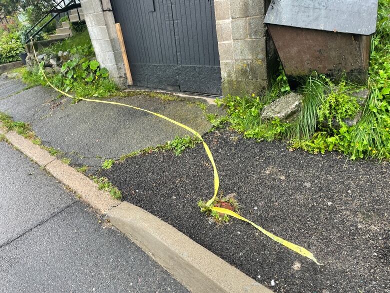 Yellow police tape on a sidewalk.